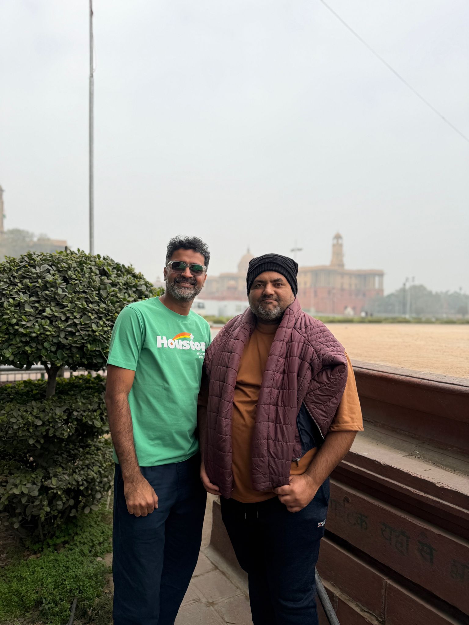 Two men stand side by side in front of a building.
