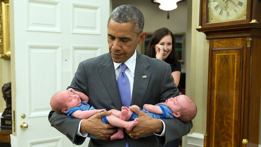 President Barack Obama carries twins of staffer
