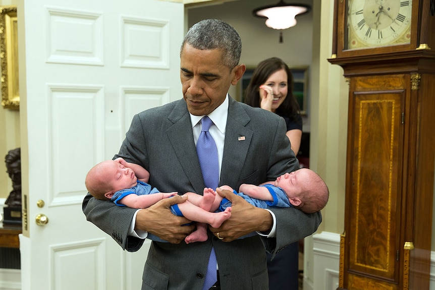 President Barack Obama carries twins of staffer