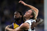 A West Coast AFL player pushes against a Geelong opponent as they look to the air for the ball.