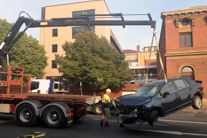 A crane lifts damaged car on Davey Street Hobart