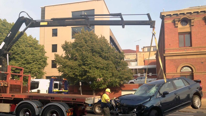 A crane lifts damaged car on Davey Street Hobart