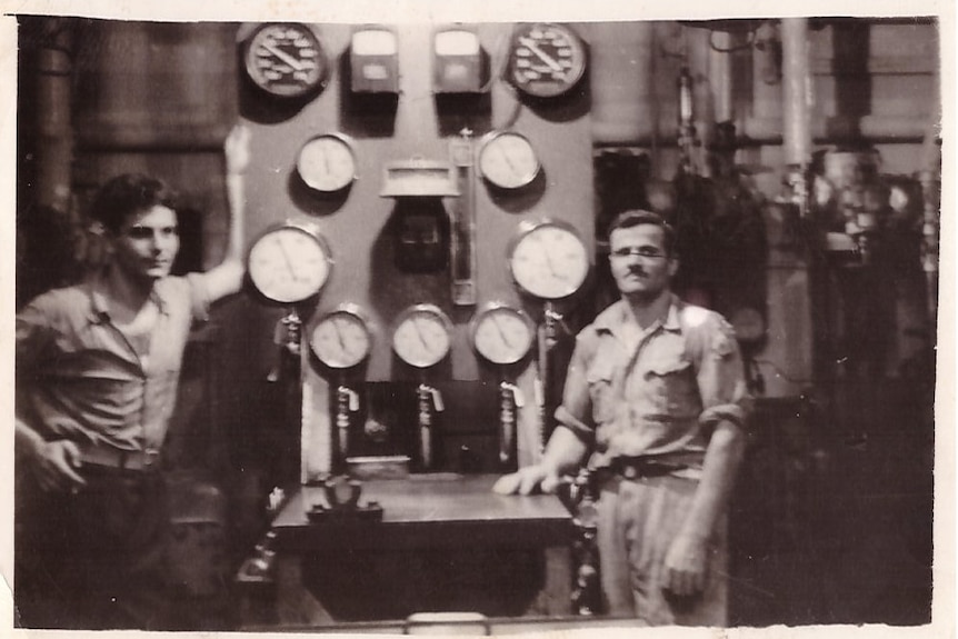 Two men in the boiler room of a ship, black and white photo.