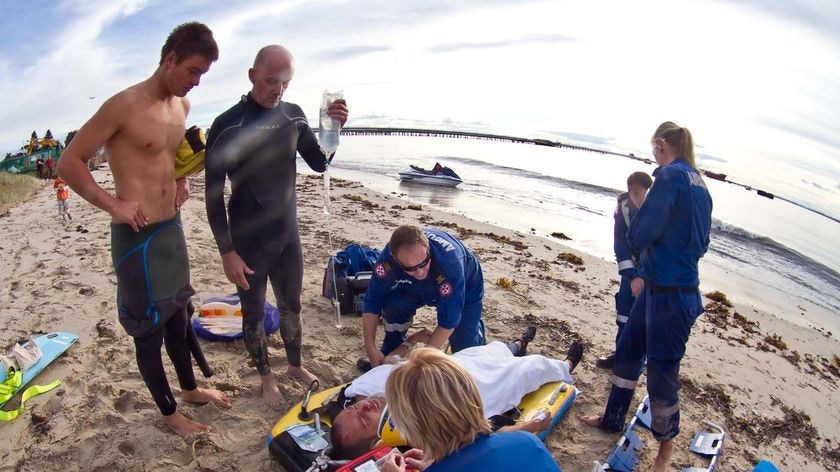 Bondi Rescue lifeguard Kobi Graham is treated for injuries by a an ambulance crew