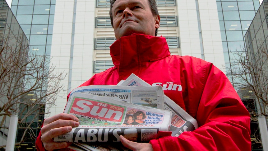A Sun newspaper seller stands outside News International headquarters in Wapping in London on February 17, 2012. Rupert Murdoch will address hostile journalists at his British newspaper arm on Friday, many of them fearful after the recent arrests of senior staff at the mass-selling Sun tabloid over allegations of widespread criminality.