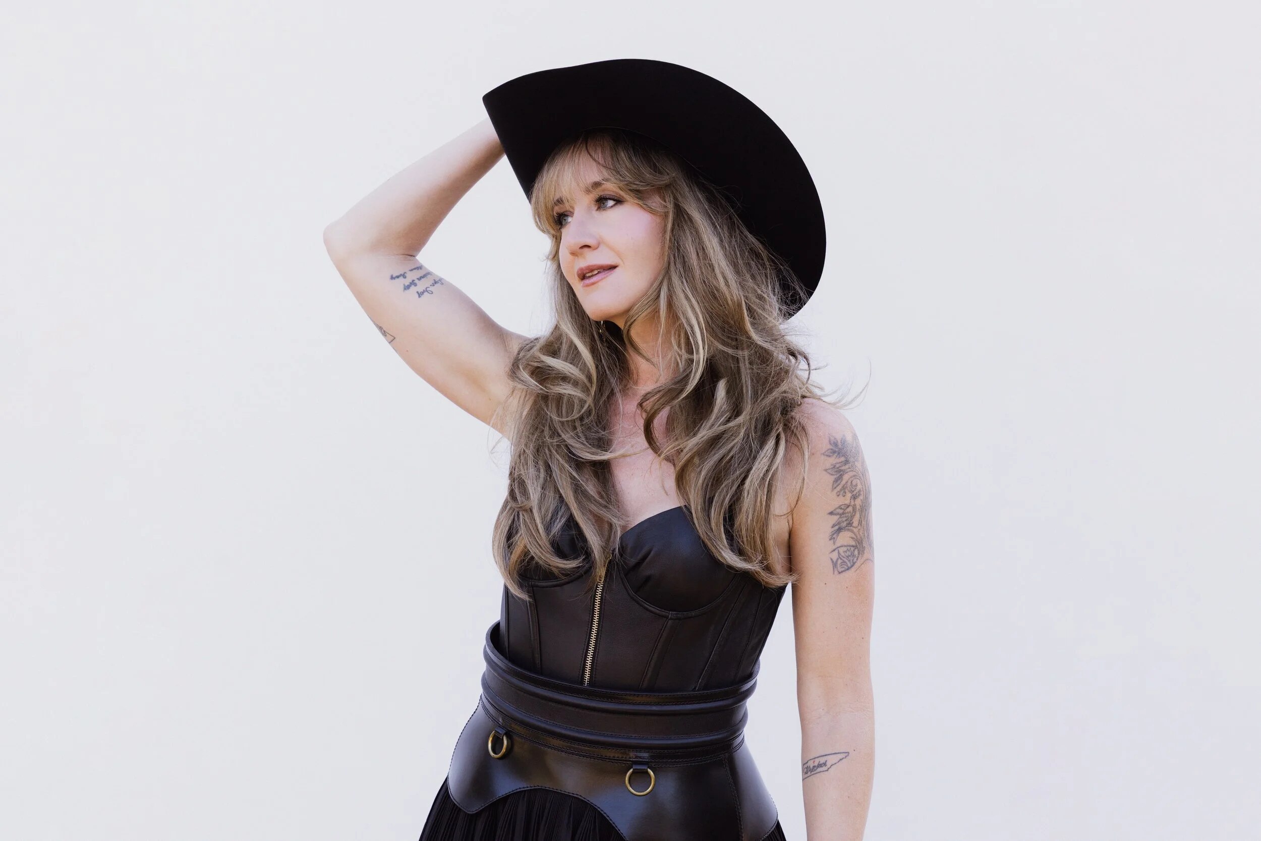 Margo wears a black cowboy hat and black outfit