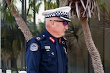 Assistant Commissioner Nick Anticich is wearing a navy NT Police uniform, a cap, and sunglasses as he leaves court.
