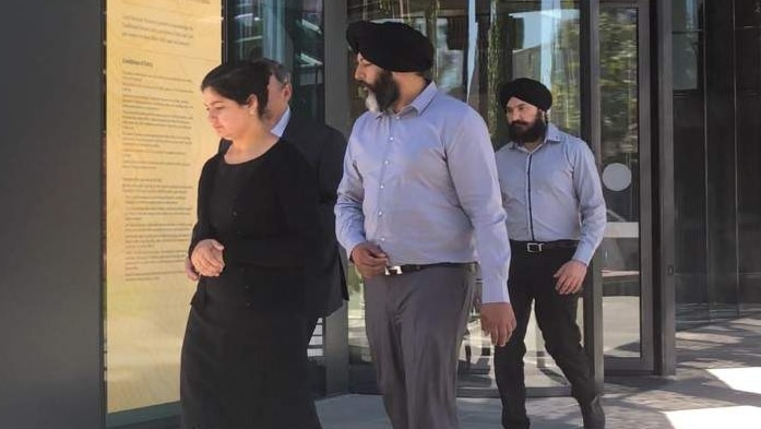 Jatinder Panesar walks outside a court building, accompanied by two men and a woman.