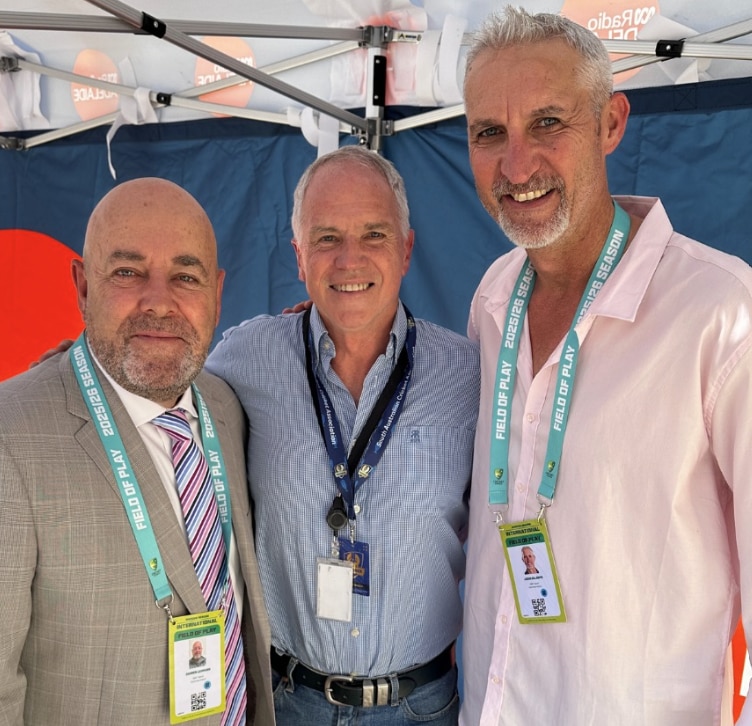 Três homens com cadarços sorrindo alinhados do mais baixo para o mais alto, da esquerda para a direita