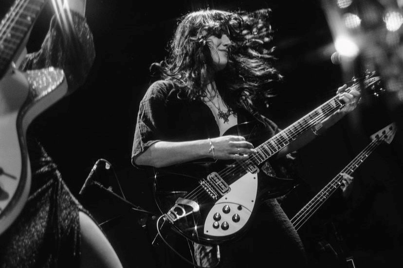 A black and white photo of a woman playing electric guitar 