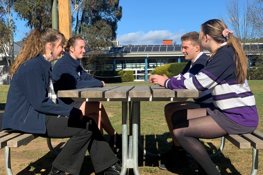 Four teenagers sitting at on school bench
