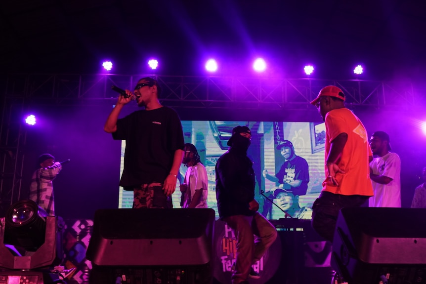 A group of men on a stage with one of them holding a microphone