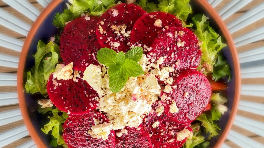 A salad with sliced dragon fruit around it.