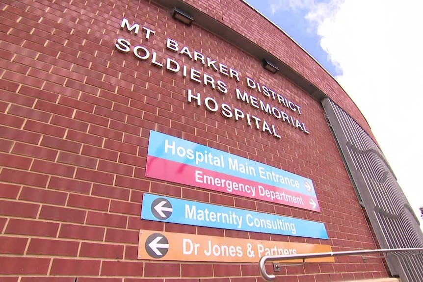 A red brick building with signs pointing to the hospital entrance and emergency department