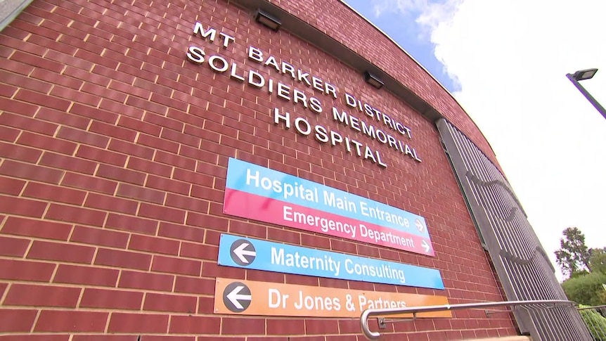 A red brick building with signs pointing to the hospital entrance and emergency department