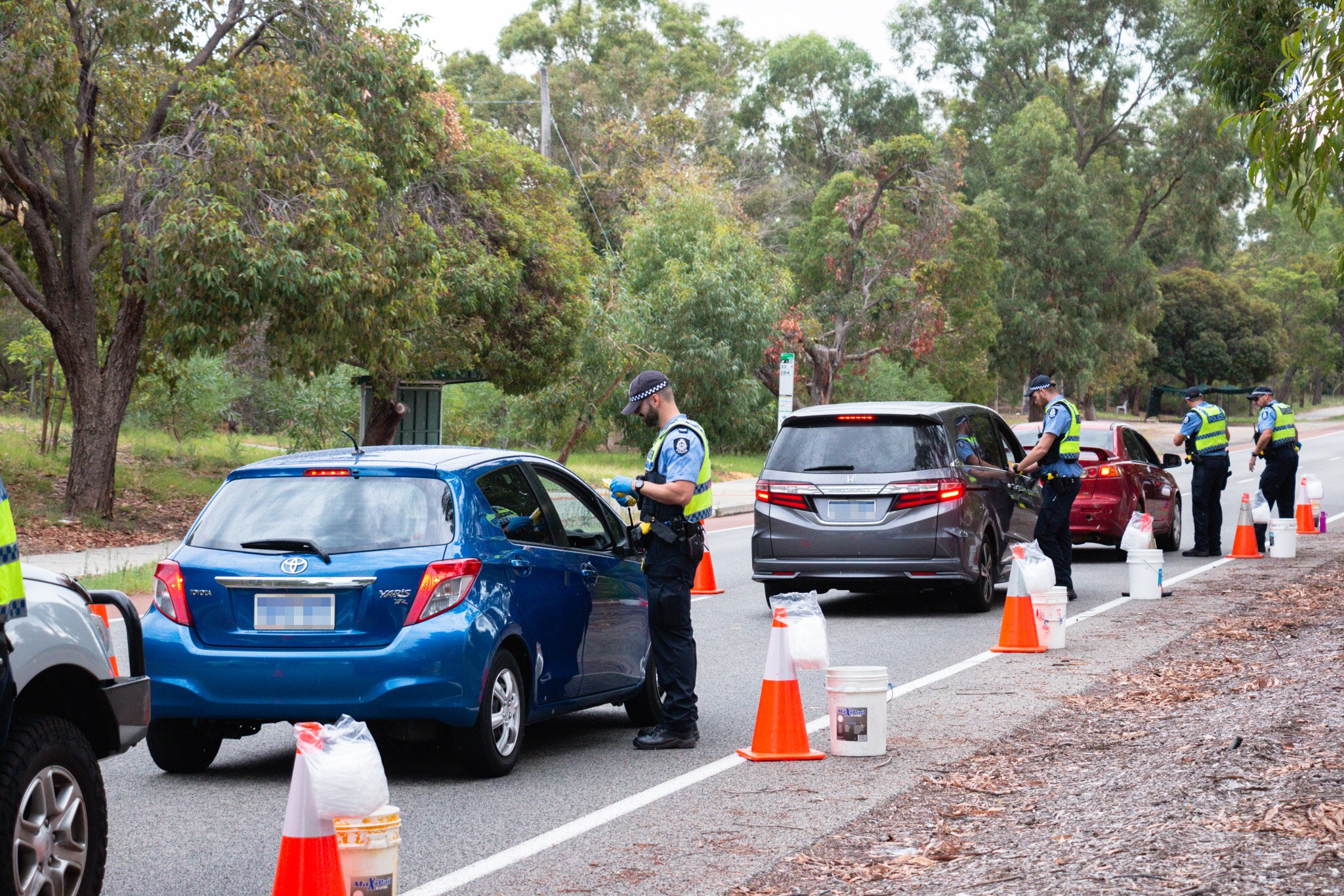 A row of cars with police officers standing alongside them carrying out RBTs.