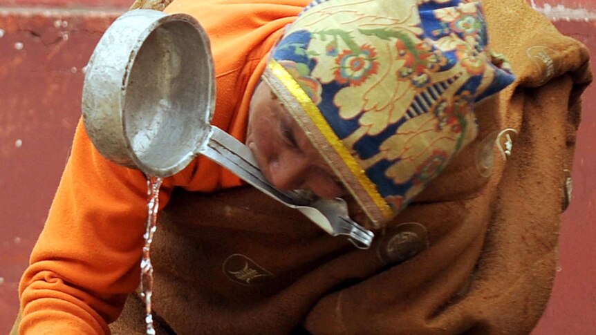 A Tibetan man washes his hands at Seda Monastery.