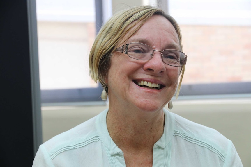 A woman in glasses smiles