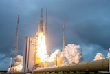 Rocket launches with fire and plumes of smoke in cloudy weather.
