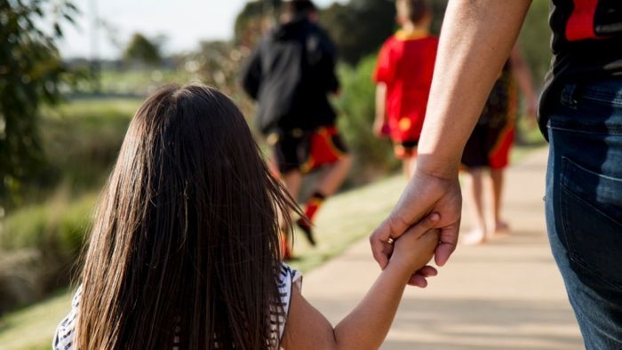 A girl holding hands with an adult.