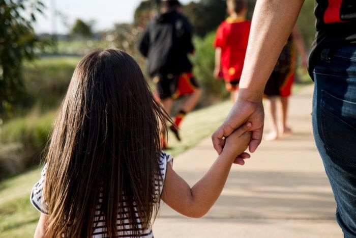 A young Aboriginal girl holding hands with an adult