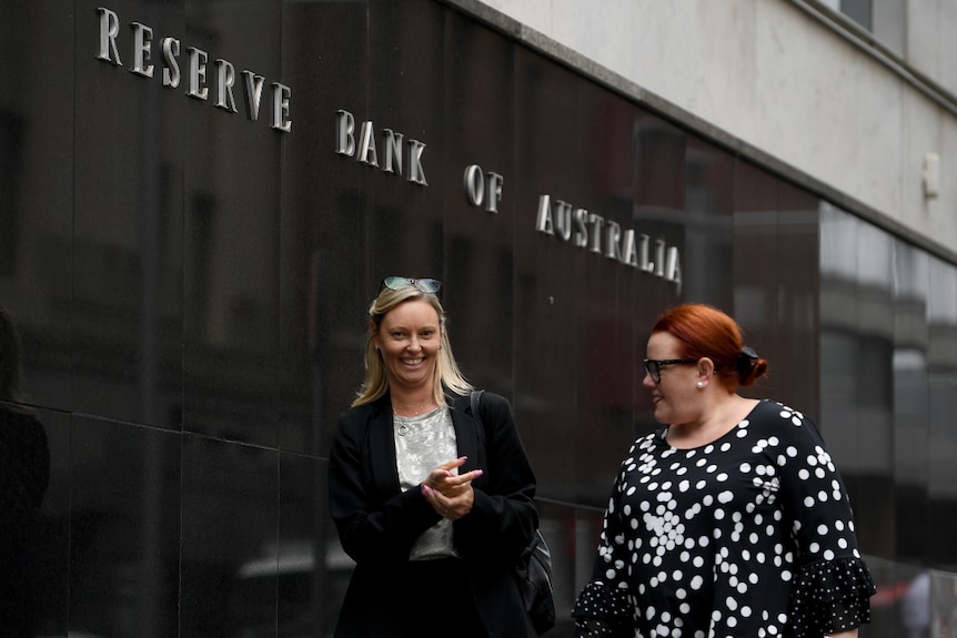 Two women wearing work attire walking past the Reserve Bank of Australia offices in Sydney.