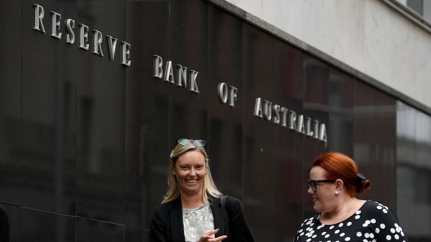 Two women wearing work attire walking past the Reserve Bank of Australia offices in Sydney.