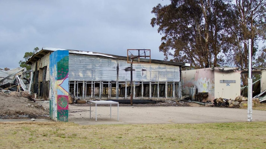 There are two fire damaged buildings, a burnt basketball ring, but a netball ring surives.