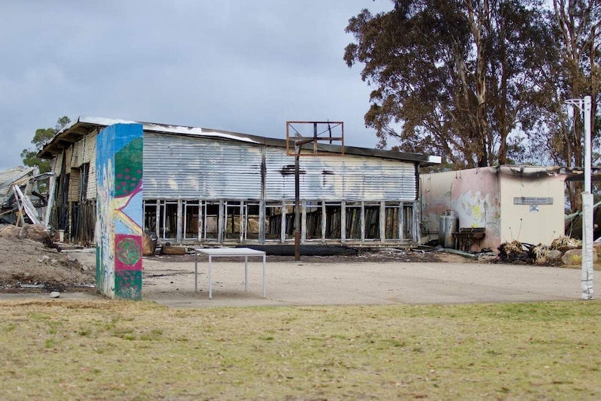 There are two fire damaged buildings, a burnt basketball ring, but a netball ring surives.