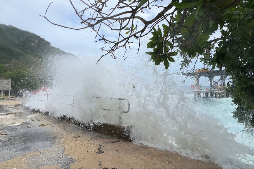 A large wave hits a sea wall with spray visible. 