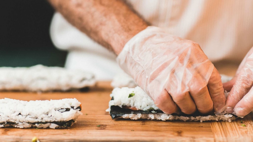 A chef rolls sushi.