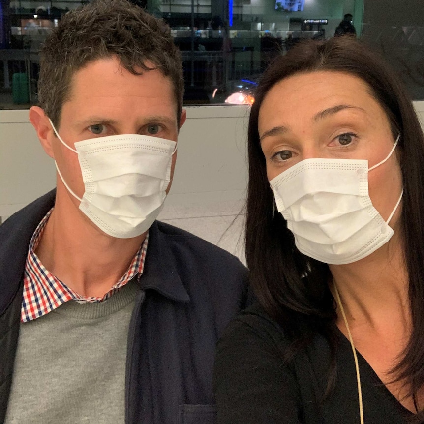 A woman and a man wearing masks take a selfie.