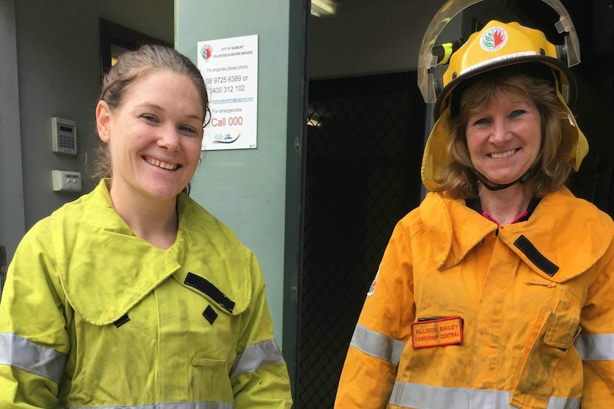 Two women in firefighting uniforms and helmets.