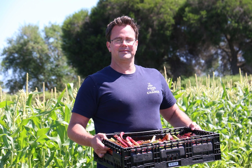 Matt Donovan holds a crate of produce at his charity's farm in Clayton South.