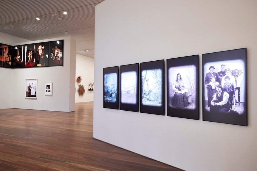 Five black and white photographs hung in a gallery (right) and the on the left a series of colour photographs