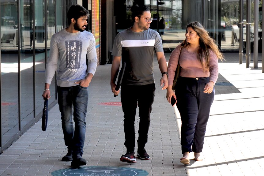 Three students walk and talk