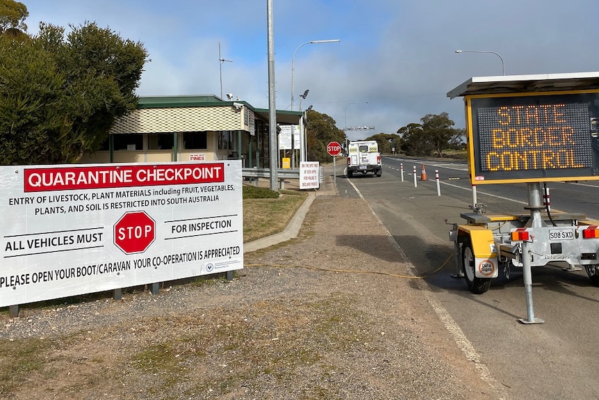 Two signs sit on the side of the road and say quarantine checkpoint and state border control.