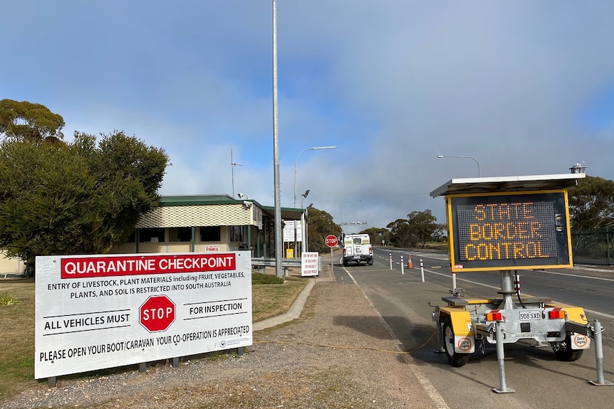 Two signs sit on the side of the road and say quarantine checkpoint and state border control.