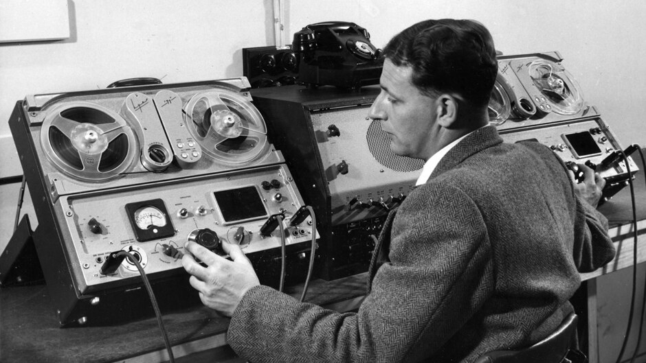 A man operates two reel-to-reel tape recorders.