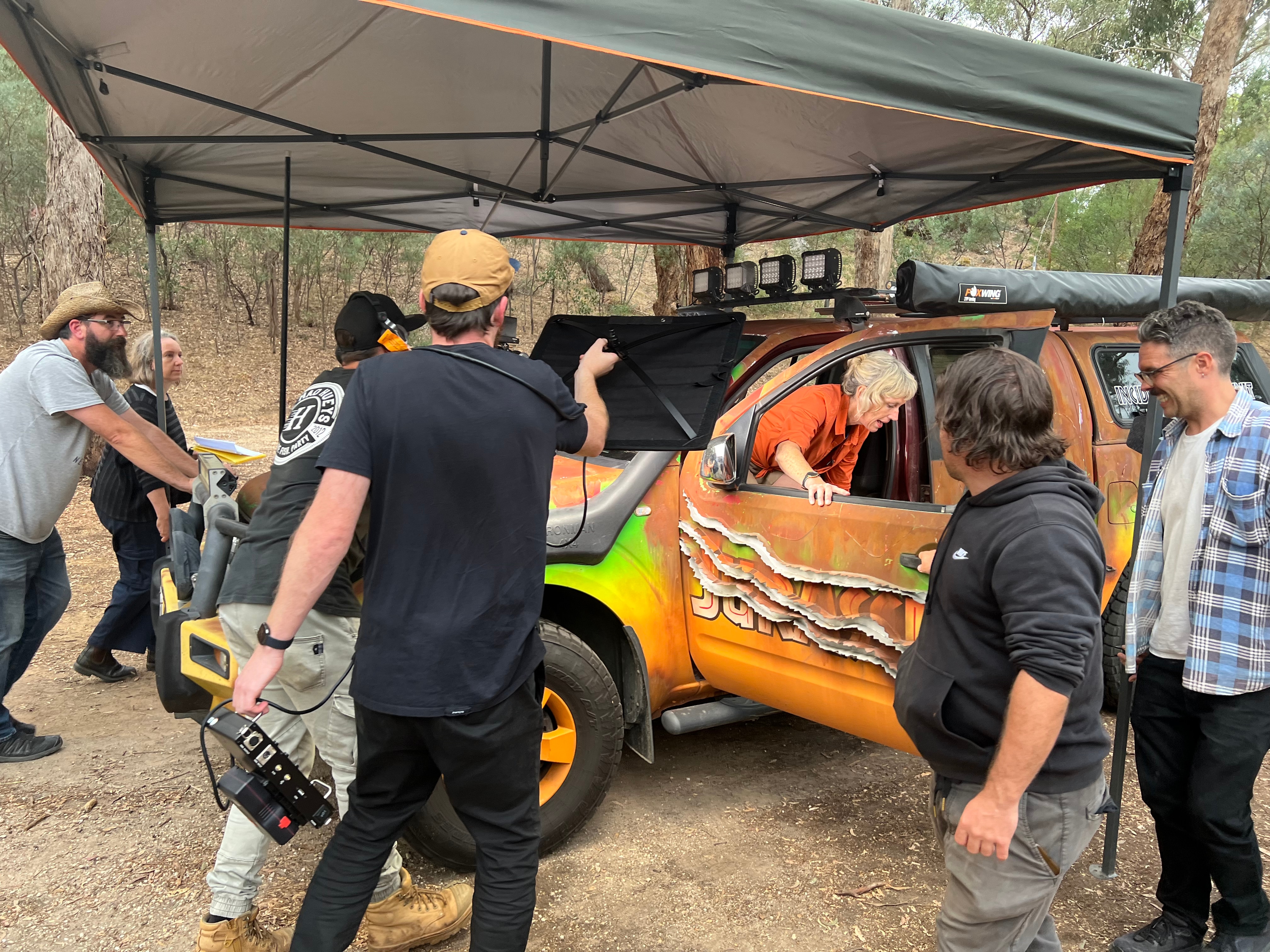 Un equipo de filmación está filmando una escena en la que un actor sale de un coche.