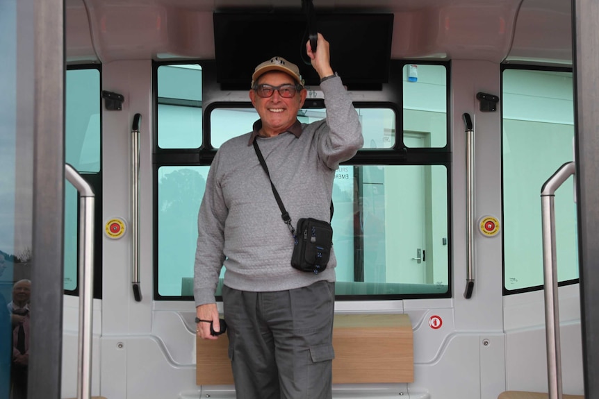 One of the elderly holding onto the railing on the bus