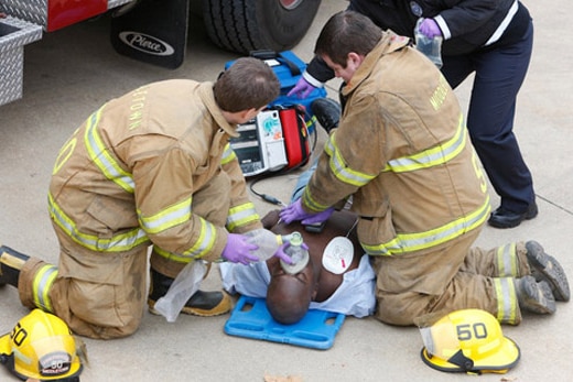 Firefighters apply CPR and a breathing apparatus to a person suffering cardiac arrest