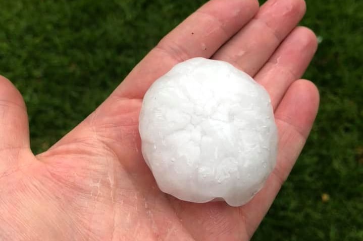 A hand holds a large hailstone
