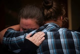 Two people hug at a fire recovery centre.