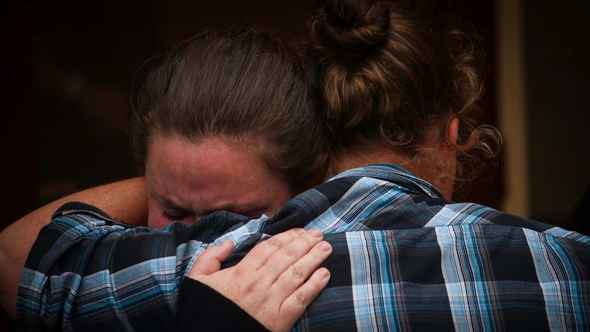 Two people hug at a fire recovery centre.