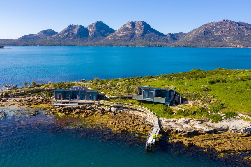 A group of accommodation buildings on an island with a backdrop of granite mountains