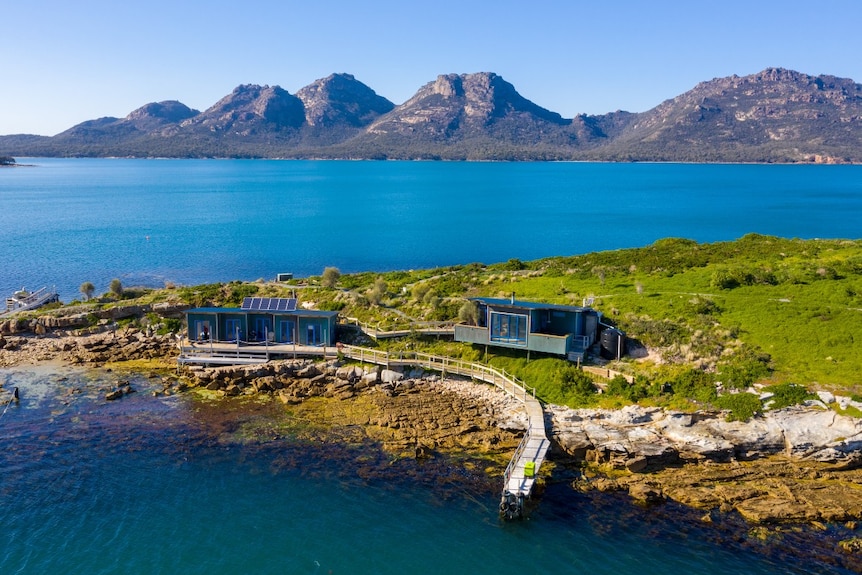 A group of accommodation buildings on an island with a backdrop of granite mountains