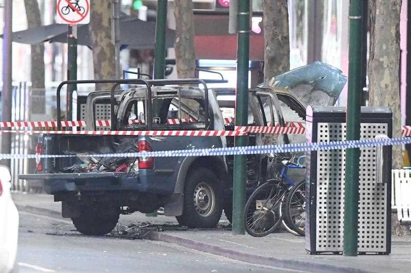 Burnt-out vehicle on the footpath surrounded by police tape