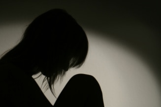 Silhouette of woman on chair in a curled up position.