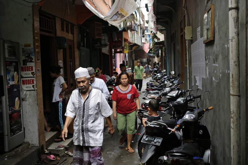 Residents walk through a narrow alleyway crowded with motorbikes in Tambora, Jakarta, near where Siti Aisyah used to live.